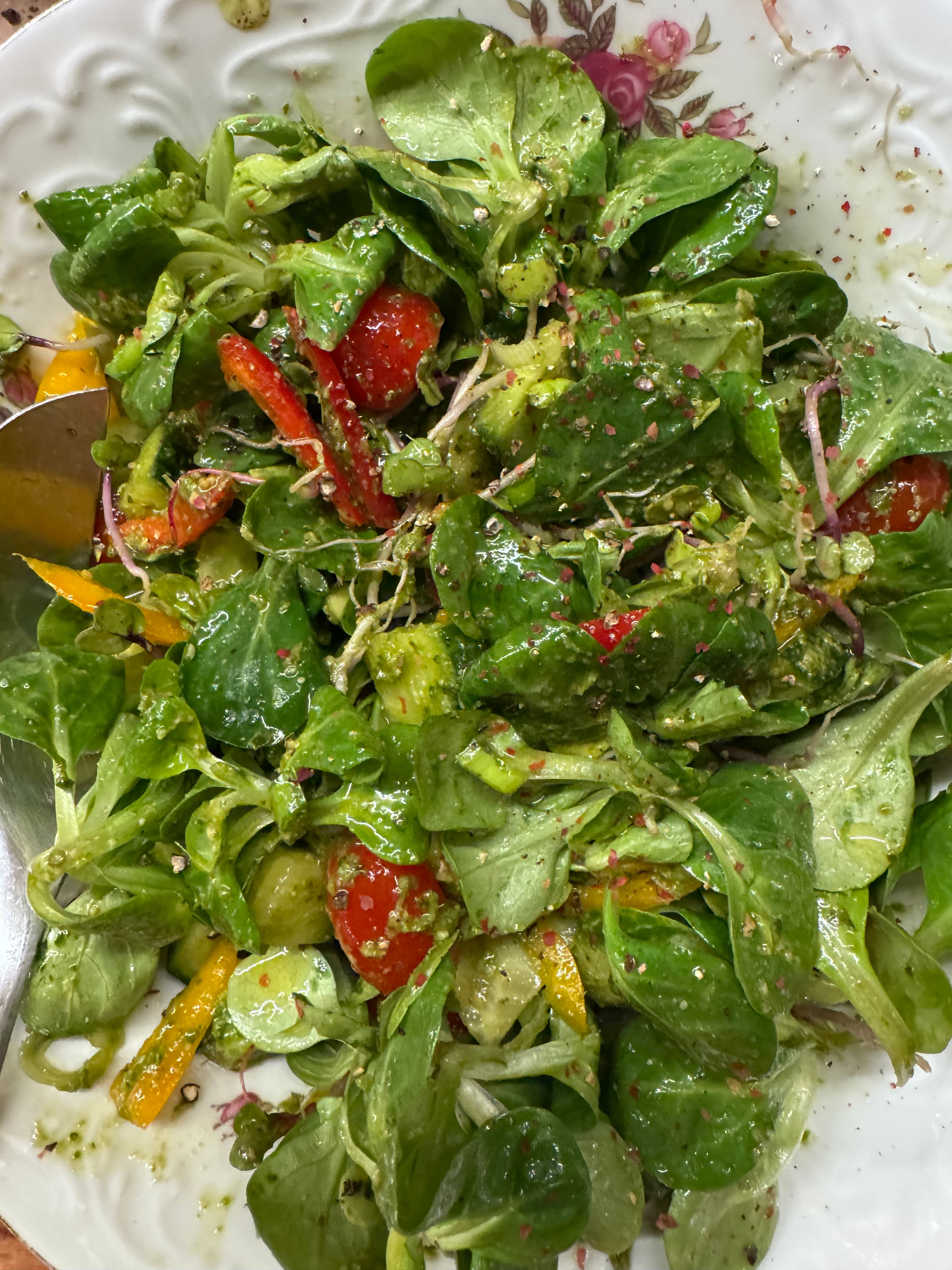 Fresh lamb's lettuce salad with tomatoes, peppers, and sprouts, tossed in green pesto dressing.